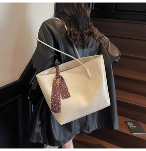 Detail of cream oversized tote bag with a polka dot scarf on a model's shoulder