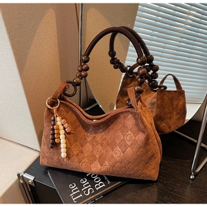 Detailed macro view of the brown suede handbag with quilted pattern and wooden bead handle