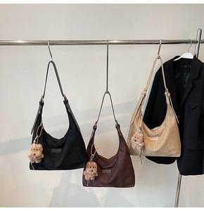 Detailed texture of suede hobo bags with adjustable straps and puppy charm pendants