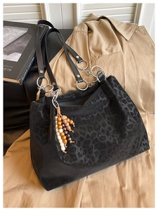 Detail of leopard print tote bag with silver ring hardware and wooden bead charm