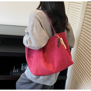 Detail of dark red faux suede tote bag featuring a decorative wooden beaded charm handle