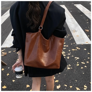 Street style shot of a brown leather tote bag carried by a model on a city crossing