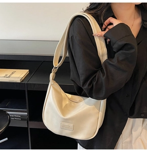 Detail of off-white crescent dumpling bag with wide strap and Mu Ran Bag brand logo