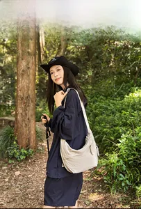 Outdoor shot of a beige half-moon crossbody bag with knot details on a model