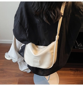 Close-up of a cream white moon-shaped crossbody bag featuring textured synthetic leather