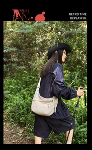 Beige crescent crossbody bag shown in outdoor hiking setting with durable nylon material