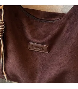 Close-up of BANATU tote bag with dark brown suede texture and decorative woven charm