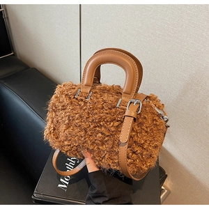 Detailed view of brown teddy fleece handbag with leather handles and silver zipper closure