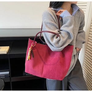 Detail of burgundy suede tote bag featuring colorful wooden bead charm and spacious interior