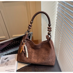 Detail of brown suede tote with wooden beads and quilted texture in a cozy setting