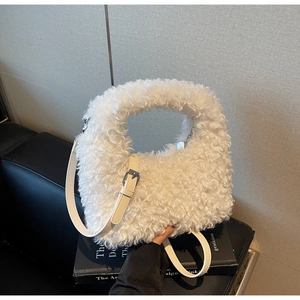 Detail of white plush handbag with adjustable leather strap and silver metal buckle