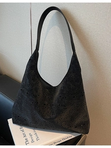 Retro black hollow-out tote bag with floral laser-cut patterns on a modern leather sofa