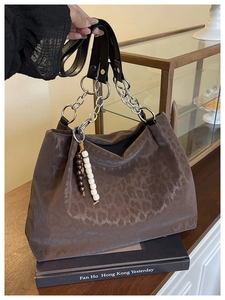 Detail of leopard print tote bag with thick silver chain handle and beaded tassel