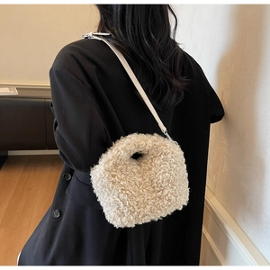 Close-up of plush cream faux fur handbag with leather strap shown against black coat