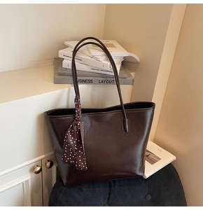 Detailed shot of dark brown leather tote bag featuring a polka dot silk scarf handle accent