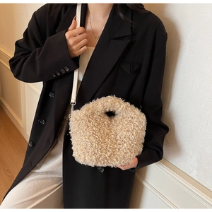 Detail of beige plush teddy handbag featuring soft texture and thin leather shoulder strap