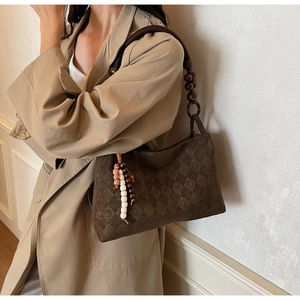 Detail of dark brown quilted shoulder bag with wooden bead strap and tassel accent