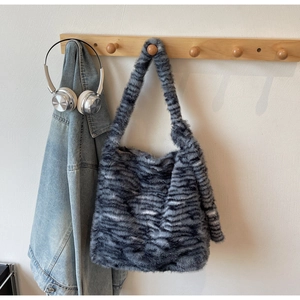 Detail of soft faux fur tote bag with black zebra stripes hanging on a wooden hook