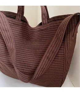 Gros plan sur la longue bandoulière lisse d'un sac cabas à carreaux marron foncé