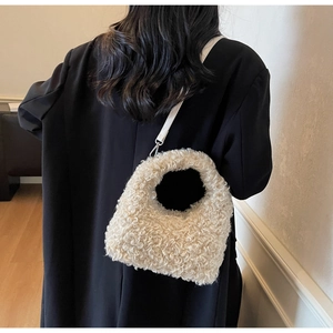 Detail of soft cream teddy fur texture and metal hook on a plush shoulder bag