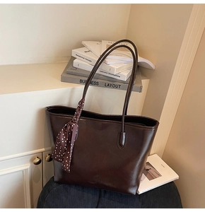 Detail of vintage brown tote bag with polka dot silk scarf handle on velvet chair