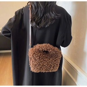 Detail of brown teddy plush shoulder bag with leather strap on a black wool coat