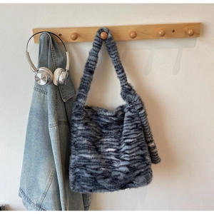 Detail of soft faux fur shoulder bag with black and grey tiger stripes on a wooden rack