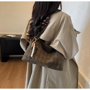 Detail of vintage brown suede shoulder bag featuring a unique wooden bead strap and tassel