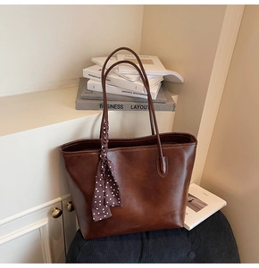 Detail of dark brown faux leather tote bag with elegant polka dot scarf accessory