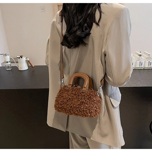 Brown fluffy lamb wool crossbody bag with leather handle shown on a model's shoulder