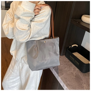 Detail of grey nylon tote bag with brown leather straps and gold magnetic clasp
