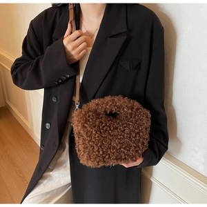 Detail of soft brown plush crossbody bag with leather strap on a model wearing black blazer