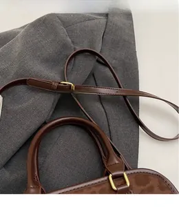 Close-up of vintage brown crossbody bag with adjustable shoulder strap and gold hardware
