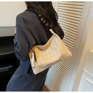 Detail of hobo shoulder bag with beige quilted texture and unique wooden bead strap