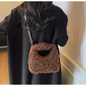 Detail of dark brown faux shearling handbag with plush texture and leather strap