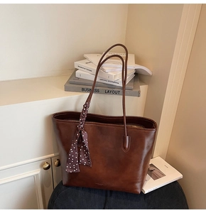 Close-up of brown leather tote bag with polka dot scarf detail and high-end texture