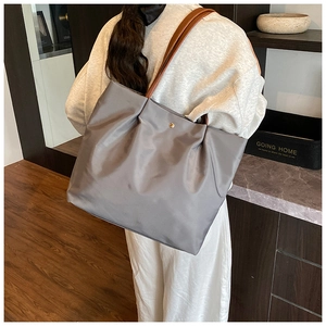 Detail of grey nylon tote bag with brown leather handles and secure gold snap button