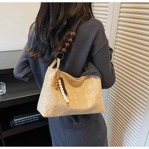 Detail of beige quilted suede tote bag featuring unique dark wooden beaded shoulder strap