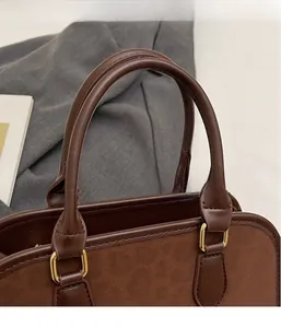 Detail of dark brown matte leather handbag with gold D-ring hardware and suede stitching