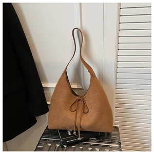 Detail of a brown suede hobo bag with bow tie on a silver suitcase for daily commute