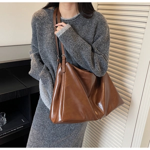 Detail of glossy vintage brown leather texture and adjustable straps on a large tote bag