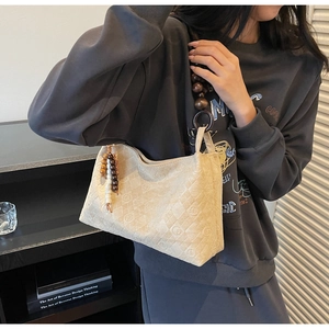 Detail of beige quilted shoulder bag featuring unique large wooden bead strap and tassel