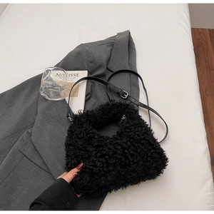 Detail of black faux fur plush handbag with leather strap on a minimalist background