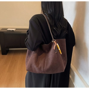 Detailed texture of brown suede tote bag with colorful beaded ethnic style charm