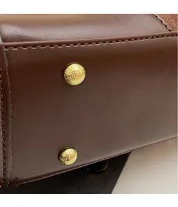 Detail view of golden textured metal studs on a dark brown leather vintage bag