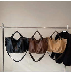 Dettaglio delle borse hobo vintage nei colori nero, caffè e beige su supporto metallico