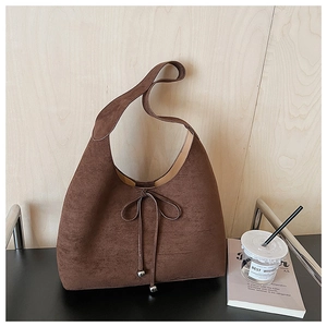 Detailed close-up of brown suede hobo bag with lace-up bow and metallic beads
