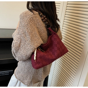 Detail of dark red quilted tote with vintage wooden bead strap and velvet texture