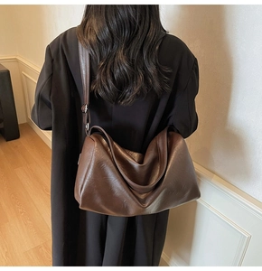 Brown large capacity tote bag shown on shoulder in a minimalist indoor lifestyle setting