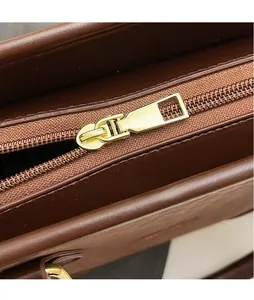 Detail of premium gold-toned metal zipper slider on a textured brown leather crossbody bag